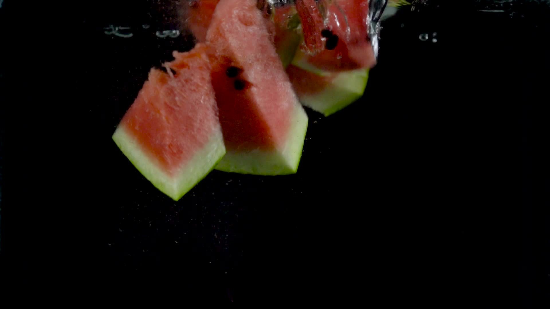 Pieces of watermelon fall and float in water, black background. Slow motion 22132833 Stock Video