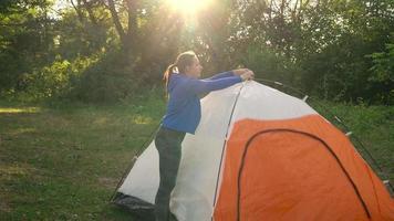 Woman is putting a tourist tent in the forest video