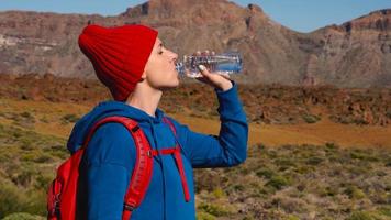 Hiking woman drinking water after hike on Teide, Tenerife. Caucasian female tourist on Tenerife, Canary Islands video