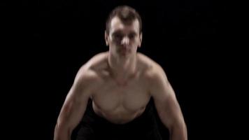 Man is doing exercises with a barbell, training on a black background in the studio video