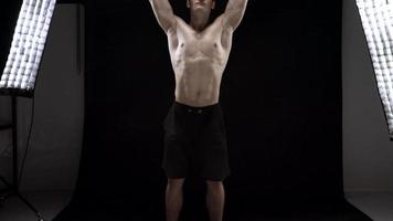 Man is doing exercises with a barbell, training on a black background in the studio video