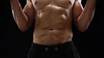 Man is doing exercises with a barbell, training on a black background in the studio. Half body in frame video