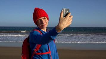 ativo caminhante mulher anda em em a de praia para a água. caucasiano jovem mulher com mochila em tenerife, canário ilhas video