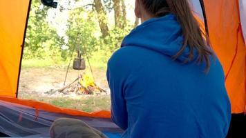 vrouw vrouw is drinken thee in een tent en op zoek Bij de brand in voorkant van haar video