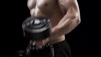 Man is doing exercises with a barbell, training on a black background in the studio video