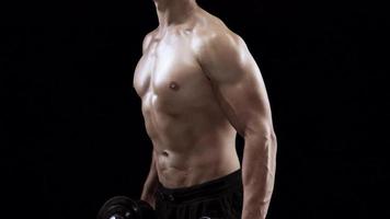 Man is doing exercises with a barbell, training on a black background in the studio video