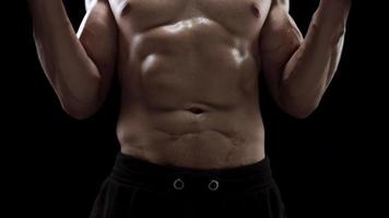 Man is doing exercises with a barbell, training on a black background in the studio video