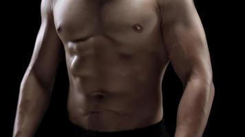 Man is doing exercises with a barbell, training on a black background in the studio video