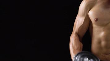 Man is doing exercises with a barbell, training on a black background in the studio. Half body in frame video