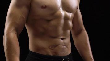 Man is doing exercises with a barbell, training on a black background in the studio. Half body in frame video