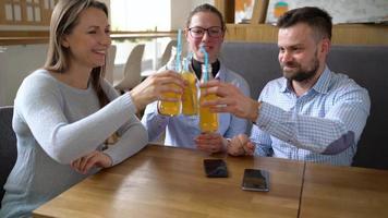 três amigos sentar dentro uma cafeteria, beber suco e ter Diversão comunicando video