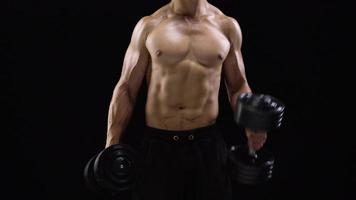Man is doing exercises with a barbell, training on a black background in the studio. Half body in frame video