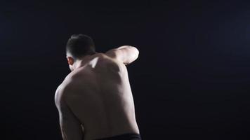 un joven hombre con su espalda convertido sombra boxeo a un rápido y amable paso. joven atleta Boxer sombra boxeo con su espalda a el cámara. video