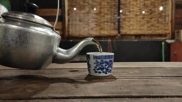 Footage of a teapot pouring hot tea into the glass causing white steam. video