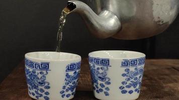 Footage of a teapot pouring hot tea into the glass causing white steam. video