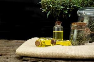 Oil cannabidiol CBD with bud marijuana in a clear glass jar on wooden and the black background photo