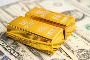 Gold bar on US dollar banknotes money, economy finance exchange trade investment concept. photo