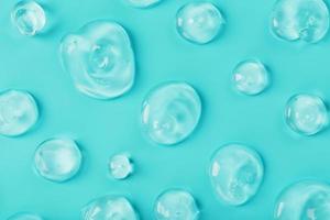 Drops of Gel with hyaluronic acid in the form of a smear of glossy texture on a cyan background. photo