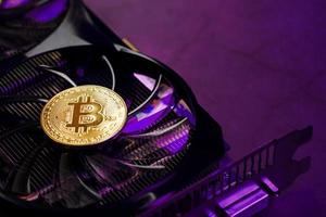 On the fans of a powerful video card, the coins of the Bitcoin cryptocurrency with a red backlight are displayed. photo