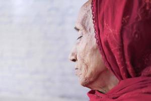 Depressed senior woman looking through window photo