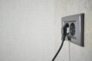 black color power cord cable plugged into wall photo