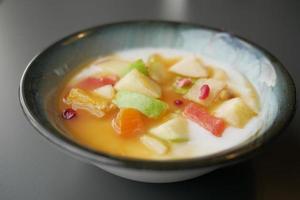 fresh fruits mixed with yogurt in a bowl on table photo