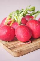 Fresh red radish bundle on chopping board on table photo