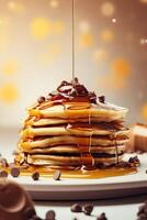 Syrup is poured down and chocolate chips are on top tall stack of golden pancakes layered on a plate with melted butter and syrup dripping down the sides of the stack. . photo