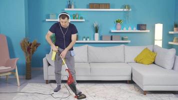 homem limpeza casa enquanto ouvindo para música com fones de ouvido. video
