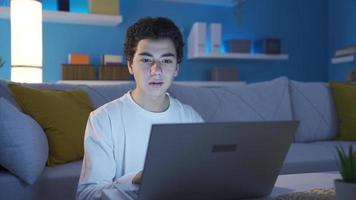 Young boy using laptop at home. Attractive concentrated young student doing homework using laptop, browsing social media, in virtual space. video