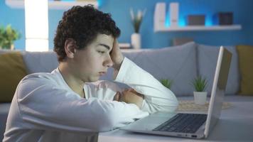 assonnato e esausto ragazzo guardare a il computer portatile. dormire volta. stanco e lento ragazzo chi è assonnato guardare a il il computer portatile in ritardo a notte è guardare a il il computer portatile. video