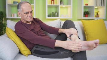 The old man with cracks in his heels. He is applying cream with her hand. Old man applying cream to cracks in the heels of his feet. Uncomfortable and unhappy with the situation. video