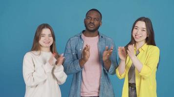 Tres amigos de diferente Razas aplaudir, felicitar. diferente carrera y etnia concepto. adolescentes de Tres diferente Razas asiático, africano y europeo mirando a cámara, aplausos. video