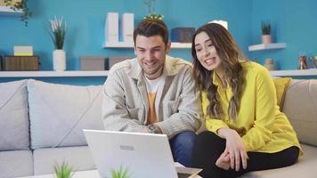 feliz jovem casal conversando com seus pais em vídeo bate-papo às lar. jovem feliz casal vídeo conversando em computador portátil com seus pais às lar. íntimo casado. video