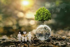 concept idea eco environment. tree growing on globe glass with world map and family icon in nature photo
