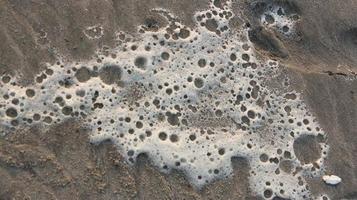 beach sand with foam and sea wave close up as a background photo