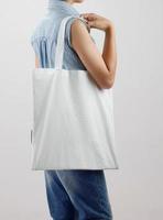 young woman holding eco cotton bag on white background photo