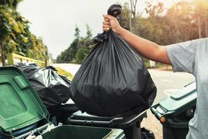woman hand holding garbage in black bag for cleaning in to trash photo