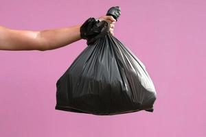 hand holding garbage bag isolate on pink background photo