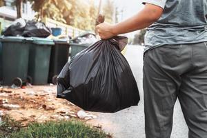 woman hand holding garbage in black bag for cleaning in to trash photo