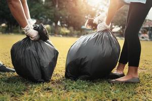 mother and children keeping garbage black bag at park in morning light photo