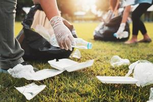 mother and children keeping garbage plastic bottle into black bag at park in morning light photo