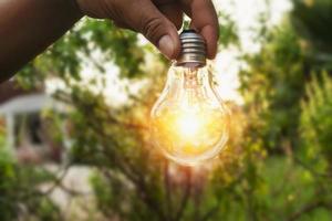 hand holding a light bulb with sunset power concept photo