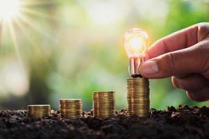 business man hand holding lightbulb money stack. idea saving energy and accounting finance concept photo