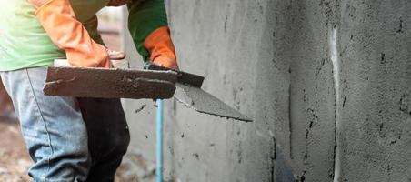 closeup hand worker plastering cement on wall for building house photo