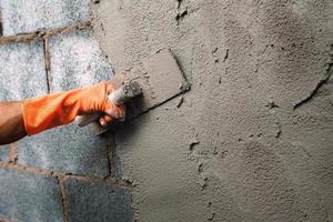 closeup hand worker plastering cement on wall for building house photo