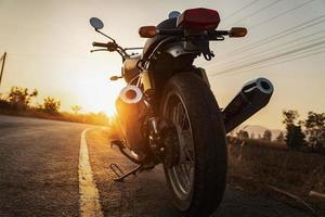 clásico estilo motocicleta en la carretera con puesta de sol foto