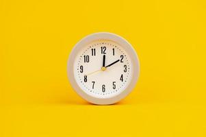 white clock on yellow background concept of time time is important to work photo