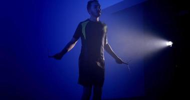un' giovane uomo esercizio con un' saltare corda, formazione nel un' buio camera video