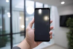 Close up view of hands holding mock up smart phone with modern office blurred background. photo